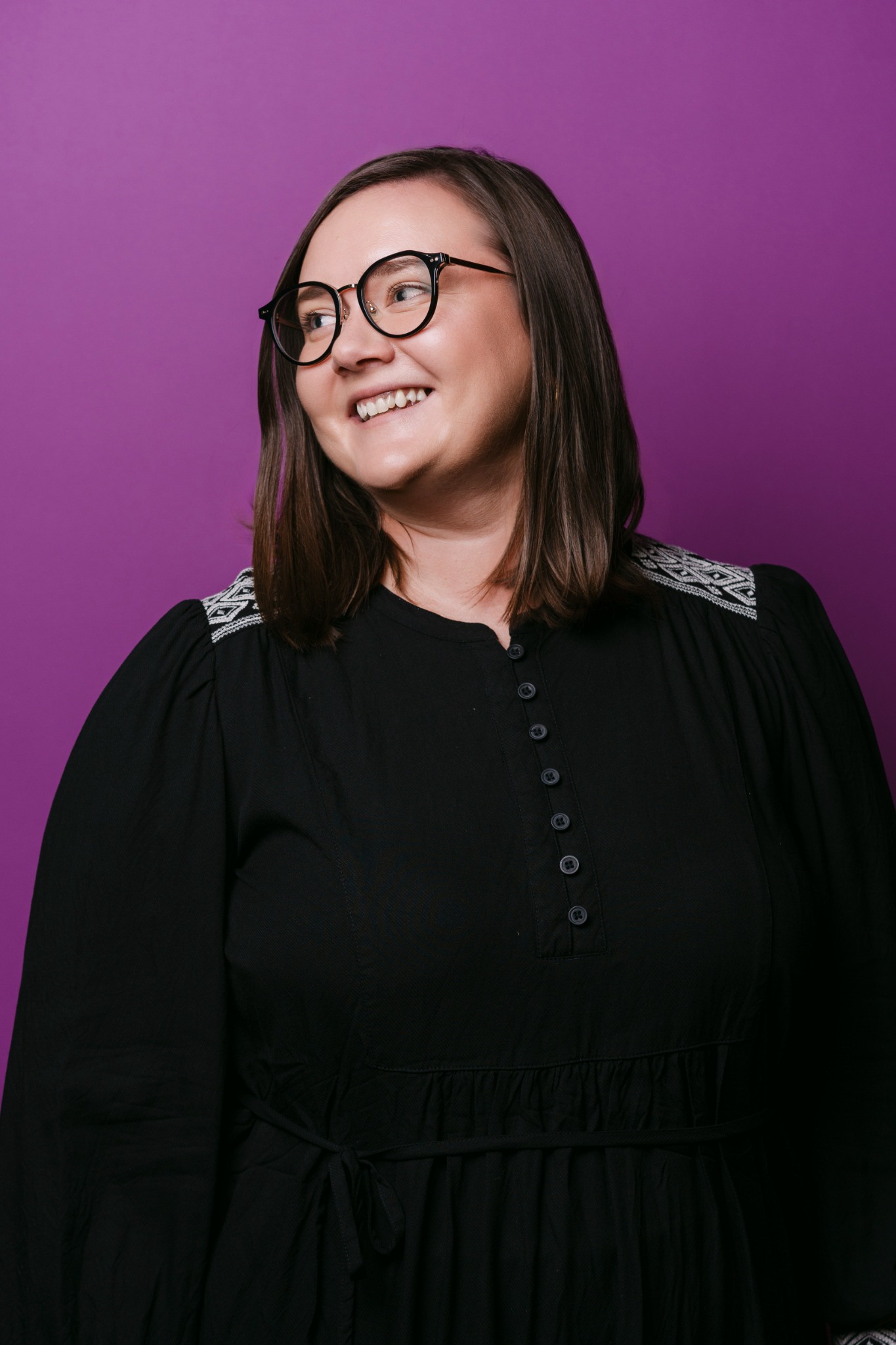 Ksenia Quinata smiling against a purple backdrop